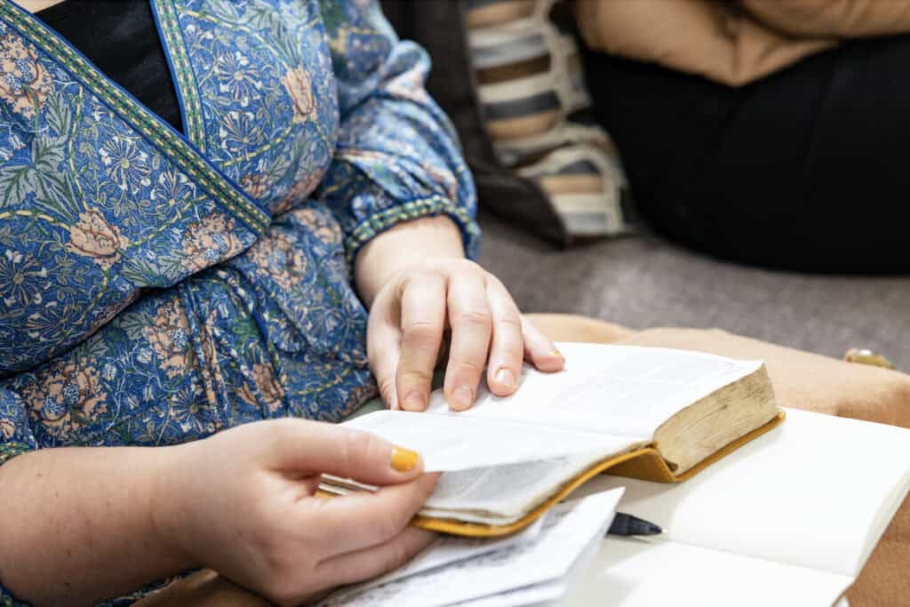 A woman holds an open notebook and Bible on her lap at Orchard Church in Los Angeles, CA
